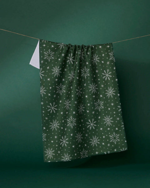 Green fabric with snowflake pattern hanging on a line against a green background