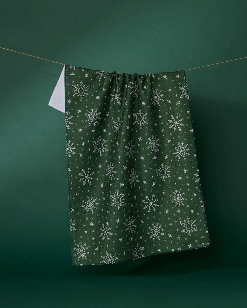 Green fabric with snowflake pattern hanging on a line against a green background